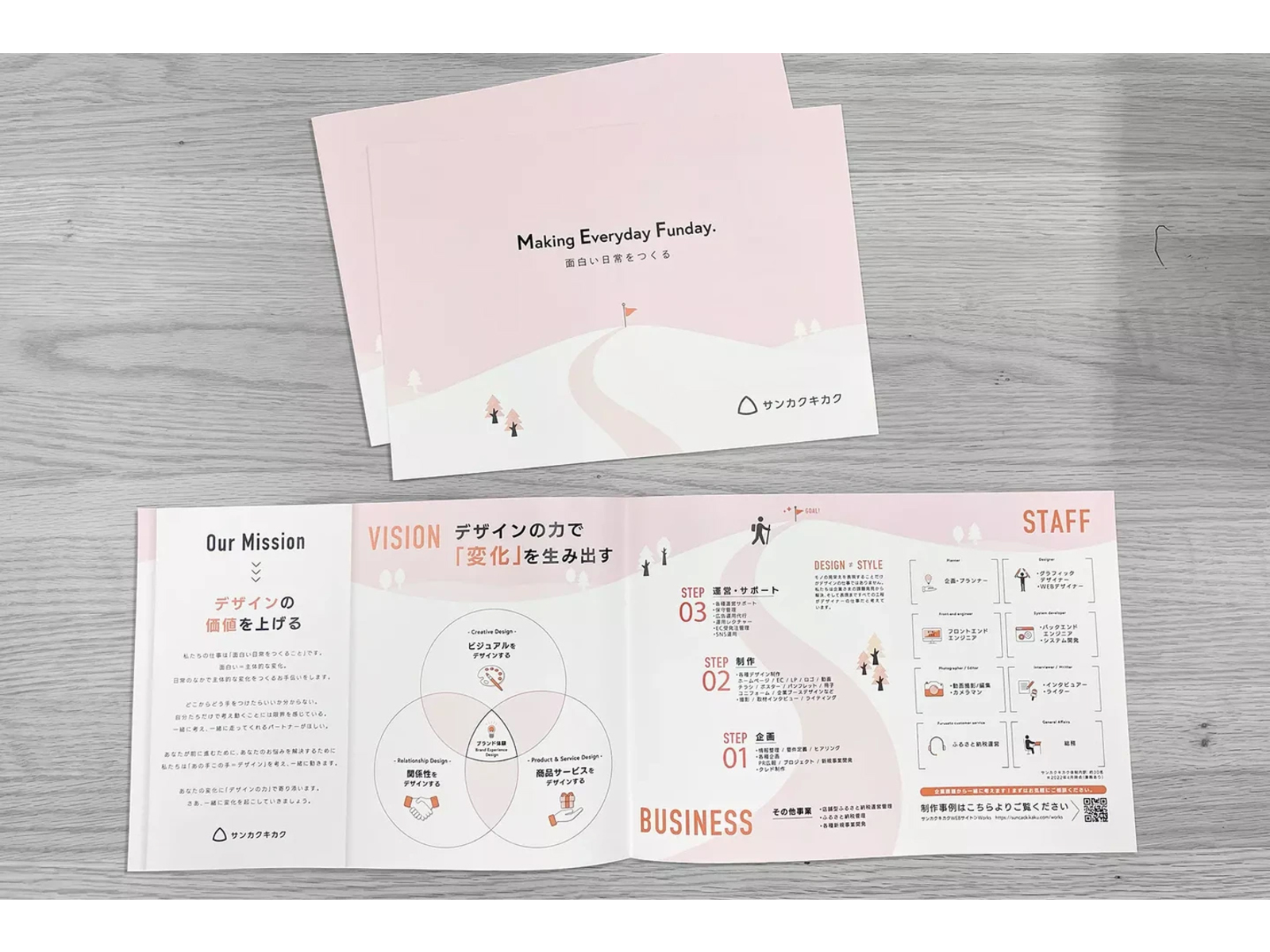「Making Everyday Funday.」の表紙と、「VISION」「BUSINESS」「STAFF」などを載せた中面を広げたピンクの会社案内パンフレット
