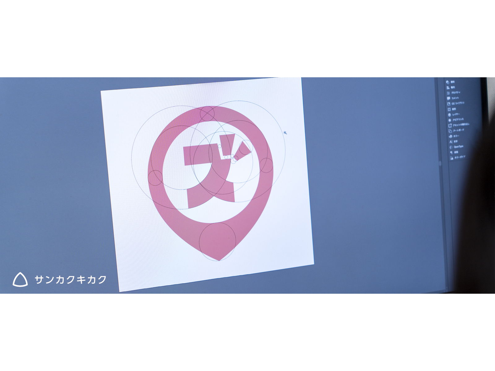 モニターに表示された、円のガイド線を重ねた「ズ」のピン型ロゴの制作画面