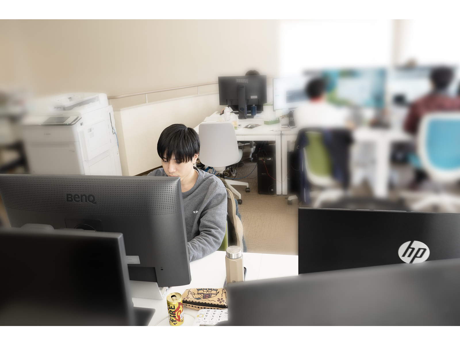 モニターが並ぶオフィスで、パソコンに向かって作業する社員