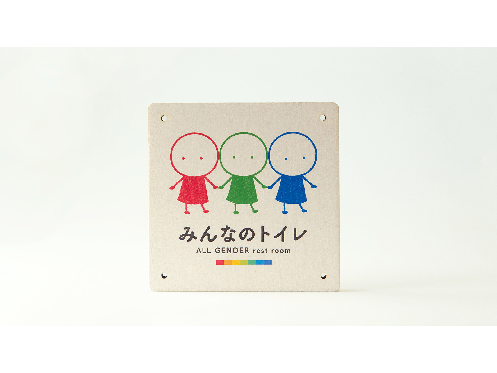 木の板のトイレサイン。手をつなぐ赤・緑・青の子どものイラストに「みんなのトイレ ALL GENDER rest room」