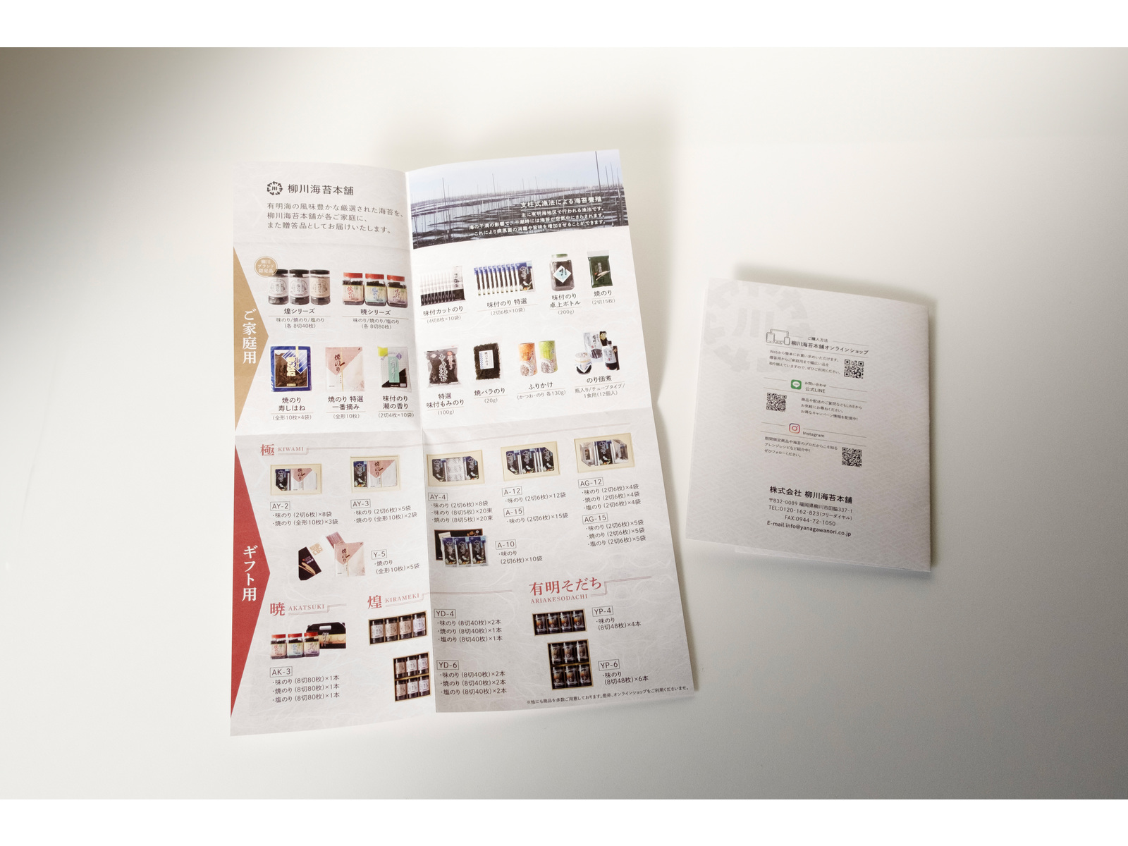 机に置いた商品パンフレット。広げた中面に「ご家庭用」「ギフト用」の海苔の商品写真が並び、横に折りたたんだ裏表紙