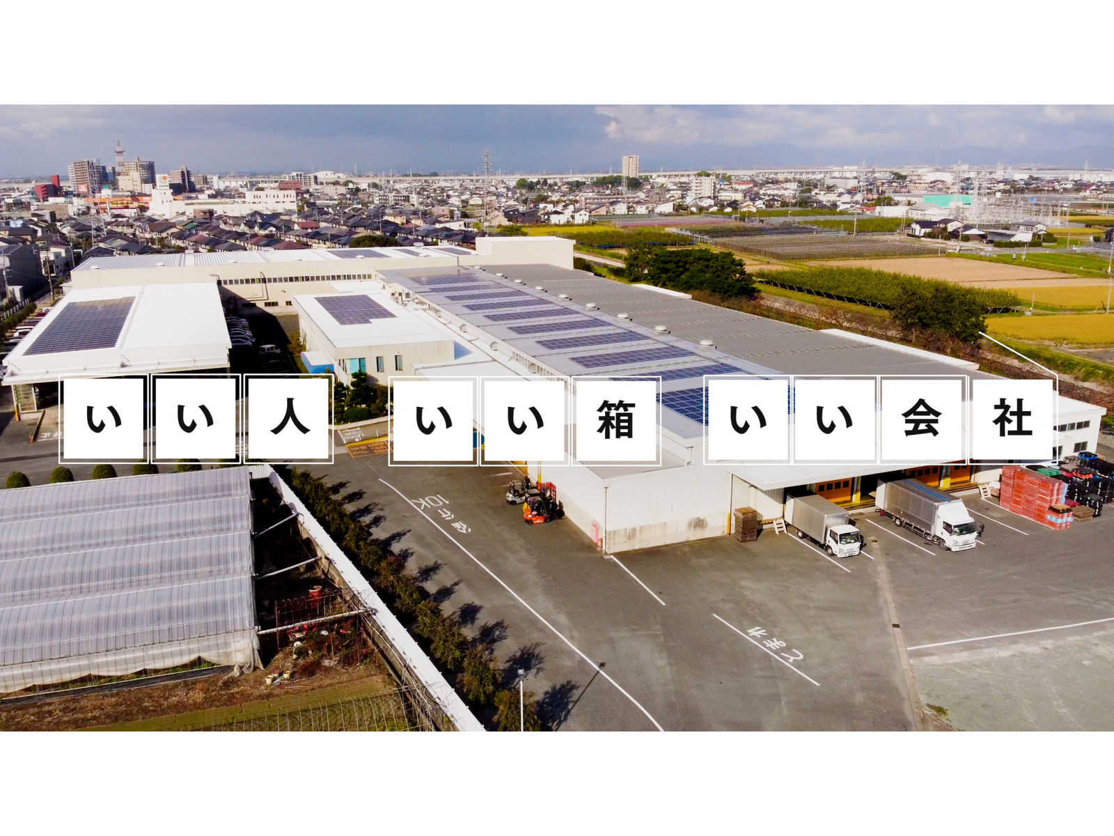 動画の一場面。屋根に太陽光パネルを載せた工場を空から写した映像に「いい人 いい箱 いい会社」の文字