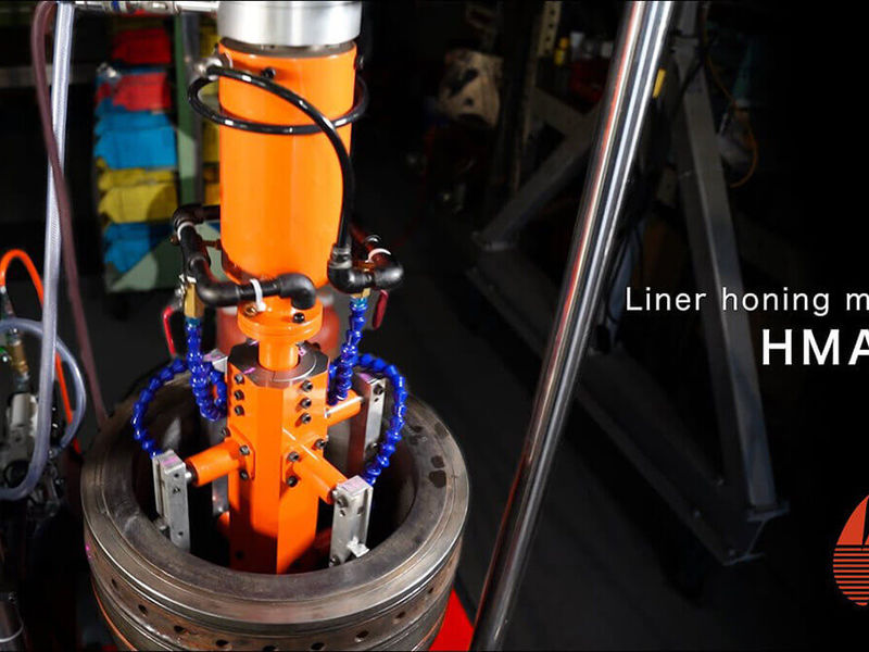 動画の一場面。暗い工場で大きなリングの中に差し込まれたオレンジ色の機械に「Liner honing machine HMA」の文字